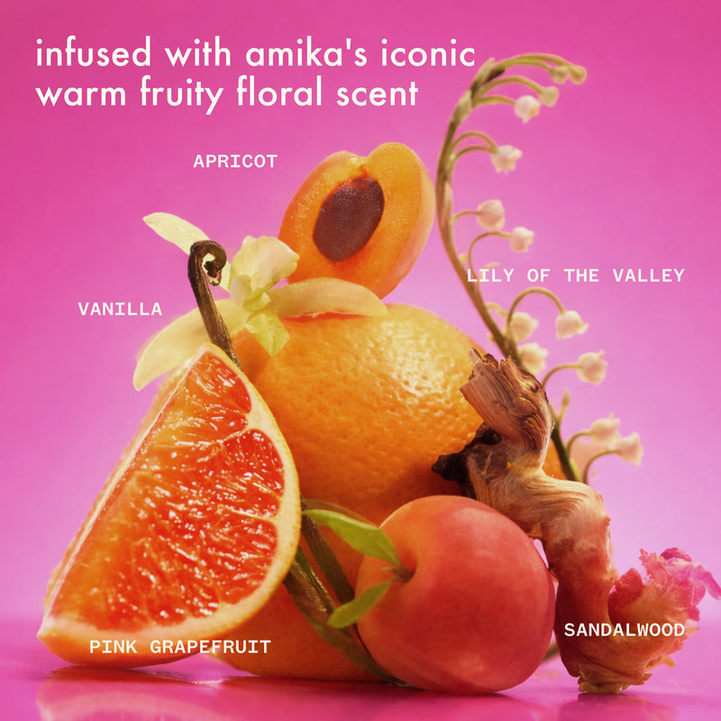 infused with amika's iconic warm fruity floral scent. a still life of apricot, pink grapefruit, vanilla, lily of the valley, and sandalwood arranged on a pink background with scent notes labeled.