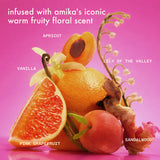 infused with amika's iconic warm fruity floral scent. a still life of apricot, pink grapefruit, vanilla, lily of the valley, and sandalwood arranged on a pink background with scent notes labeled.