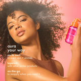 image of a model holding the amika:aura bottle and spraying the mist on skin and hair. text: "aura your way", "on its own to scent skin + strands", "layered with other amika products" and "on-the-go to reapply when you need it'