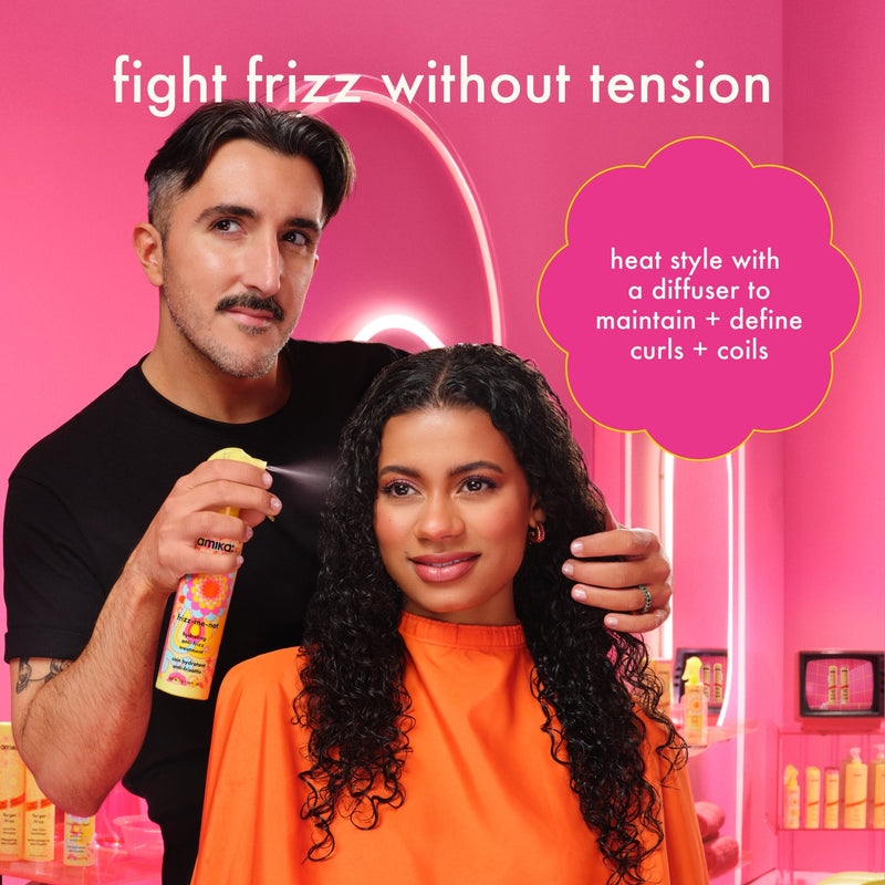image of stylist using frizz-me-not on a client's curly hair. text reads: "fight frizz without tension. heat style with a diffuser to maintain + define curls + coils." 